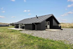 a black house with a gravel driveway at 090-Ringkobing-Klaegdalen-9 in Ringkøbing