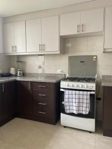 una cucina con mobili bianchi e un forno a piano cottura di Comfortable 3 bedroom house near the airport Quito and Portal a Calderón