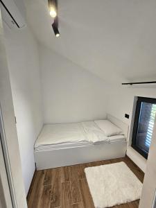 a small white bed in a room with a window at TheTomonina house with pool in Split