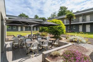 a patio with tables and chairs and an umbrella at Sure Hotel by Best Western Mont-de-Marsan in Saint-Pierre-du-Mont