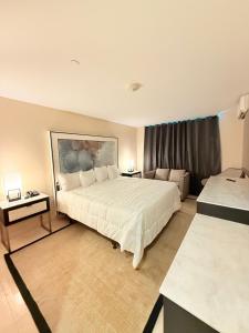 a bedroom with a large white bed and a couch at Nova Hotel Bronx in Melrose