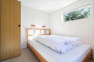 une chambre avec un grand lit blanc avec une fenêtre dans l'établissement 233-Ringkobing-Milevej-38, à Klegod