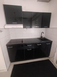 a kitchen with black cabinets and a sink at Novi dom in Gornji Milanovac