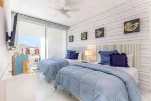two beds in a bedroom with blue and white at Marea Walk to Medano Stylish Stay in Cabo in Cabo San Lucas