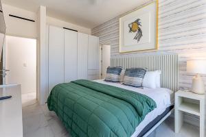 a bedroom with a bed with a green blanket at Marea Walk to Medano Stylish Stay in Cabo in Cabo San Lucas
