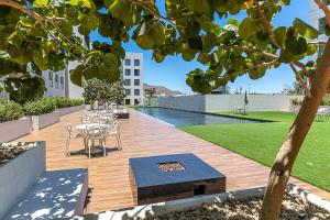 a wooden deck with a table and chairs and a pool at Marea Walk to Medano Stylish Stay in Cabo in Cabo San Lucas