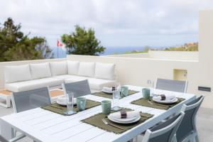 a white dining table with chairs and a white couch at Idônea in Ponta Garça