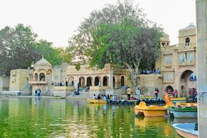 a large building with people in boats in the water at Jaisalmer Hostel Camel Castle & Safari in Jaisalmer +50 photos