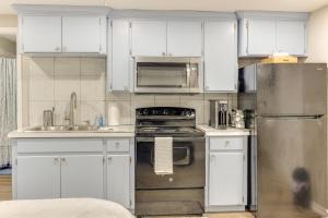 a kitchen with white cabinets and a stainless steel refrigerator at Private Yard: Pet-Friendly Studio in New Boston! in New Boston