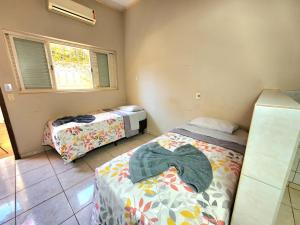 a bedroom with two beds in a room with a window at Économique Hotel in Ilha Solteira
