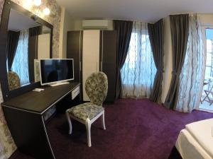 Habitación de hotel con escritorio, TV y silla en VIP Apartments Dobrevi, en Primorsko