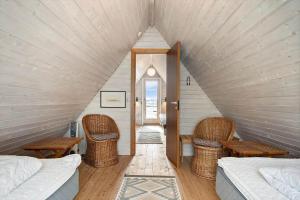 ein Zimmer mit zwei Betten und Korbstühlen auf einem Dachboden in der Unterkunft 260 Ringkøbing - Vestklitvej 13 in Klegod