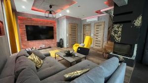 a living room with a couch and a tv at Domki i dom w sadzie Stegna z podgrzewanym basenem - prywatne jacuzzi przy domu in Stegna