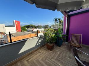 a balcony with a purple wall and a table and chairs at Apto aconchegante e familiar em BC in Balneário Camboriú