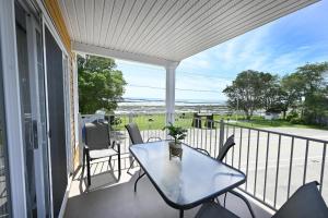 een terras met een tafel en stoelen op een balkon bij Condo Bord de fleuve Piscine - Les Voitures d'Eau in L'Isle-aux-Coudres