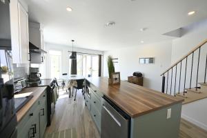 a large kitchen with a wooden counter top at Condo Bord de fleuve Piscine - Les Voitures d'Eau in L'Isle-aux-Coudres +46 photos