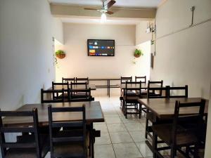 a dining room with tables and chairs and a flat screen tv at Économique Hotel in Ilha Solteira