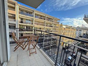 Un balcón con una mesa y sillas y un edificio. en Calme et ensoleillé balcon quartier Port Nice, en Niza