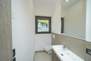 Un baño con inodoro, lavabo y ventana. en Attico La Pergola, en Moniga del Garda 25 fotos más