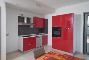 Una cocina con gabinetes rojos y un fregadero. en Attico La Pergola, en Moniga del Garda