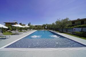 una gran piscina con sillas y sombrillas en Attico La Pergola, en Moniga del Garda