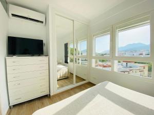 sypialnia z komodą z telewizorem i oknami w obiekcie Luminoso ático con vistas al mar en Torremolinos w mieście Torremolinos
