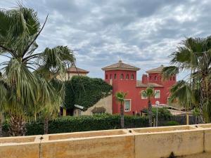a red building with palm trees in front of it at Calle Oceano atlantico 66 in El Puerto de Santa María