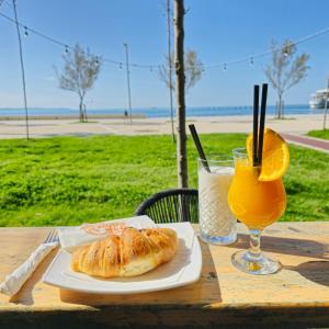a table with a plate of bread and a glass of orange juice at Alcatraz Apartment Durres in Durrës