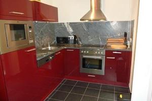 een rode keuken met een wastafel en een fornuis bij Manuela 9 by SMR Rauris Apartments - close to Spa and Gondola in Rauris