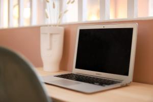 a laptop computer sitting on a desk with a vase at Stadium Pink Loft 5min Rer near Paris in Aubervilliers