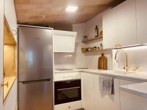 a kitchen with white cabinets and a stainless steel refrigerator at Tamariu Platja · Penthouse on Passeig del Mar. in Tamariu
