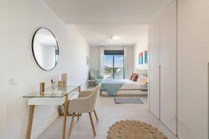 ein Schlafzimmer mit einem Bett, einem Schreibtisch und einem Spiegel in der Unterkunft Bello piso con vistas espectaculares y un spa in Sitio de Calahonda + 13 Fotos