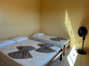 two beds in a room with a fan at Espaço Dona Deja in Bom Jesus da Lapa