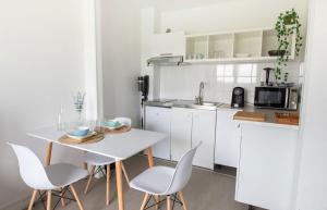 a white kitchen with a white table and chairs at Le Havre du Daiquiri - Proche Paris in Aulnay-sous-Bois