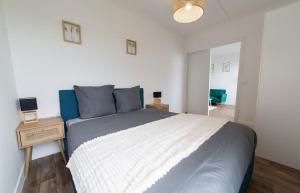 a bedroom with a large bed with a blue and white blanket at L Échappée Bellini - Proche Paris - 15min Airport in Aulnay-sous-Bois