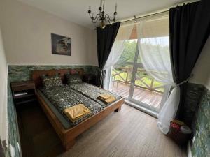 a bedroom with a bed and a large window at Sodyba "Septyni šeštadieniai" Plateliai in Paplatelė