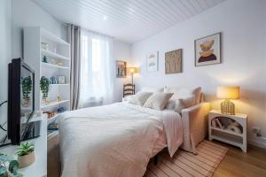 a white bedroom with a bed and a tv at LAtelier dEpinay Terracotta - Near Paris in Épinay-sur-Seine
