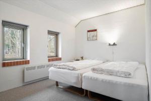 113-Ringkobing-Ahornalle-16 في Nørby: سريرين في غرفة بيضاء مع نافذتين