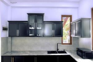 a kitchen with black cabinets and a sink at Oasis of Tranquility in Ragama