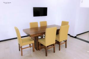 a wooden table with yellow chairs and a television at Oasis of Tranquility in Ragama