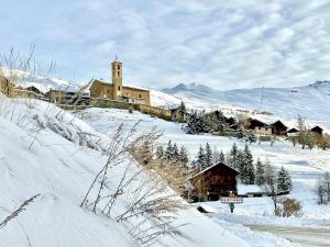 a snow covered village with a church in the distance at Casa-La Carotto Appartement pour 6 dans chalet in Saint-Véran