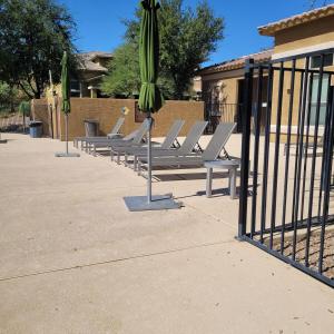 a row of chairs with umbrellas next to a fence at VILLA Verde Surprise Stadium - Resort Living in Surprise +59 photos
