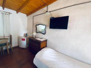 een slaapkamer met een bed en een tv aan de muur bij Posada Rio Tala in Río Tala
