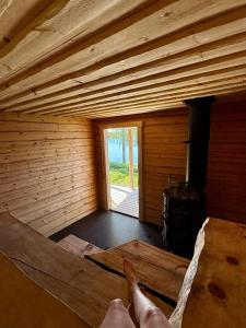 a person laying on a hammock in a wooden room at Kutulammen erämökki saunalla in Ranua