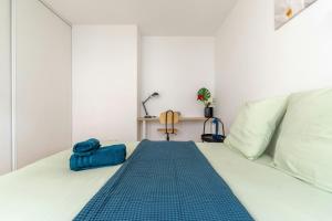 a white bed with a blue blanket on it at T2 Confort Lyonnais Métro République Garage fermé in Villeurbanne +24 photos
