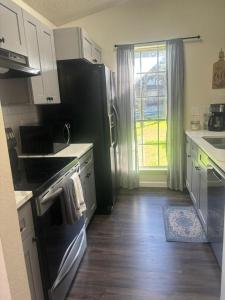 cocina con nevera negra y fogones en FORT Hambledon: SeaWorld Medical Ctr and The RIM, en San Antonio