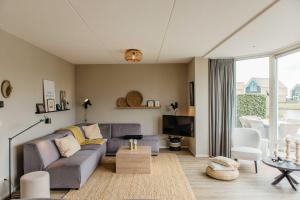 a living room with a couch and a tv at Havenvilla | 6 personen - Boutique Parc Pharshoeke in Heeg