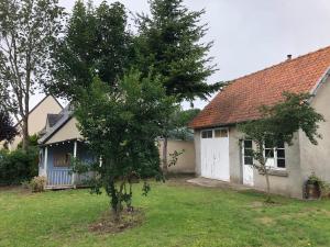 una casa con un albero di fronte a un cortile di Villa Au Beau Site Jardin, Cheminée & Mer proche a Merlimont
