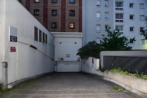 a parking lot with a white garage and a building at 5 min de Paris 10 min du Zénith et Grande Halle in Pantin