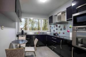 a kitchen with black cabinets and a table and chairs at Grand 4 pièces +espace bureau à 20 min Paris ! in Créteil